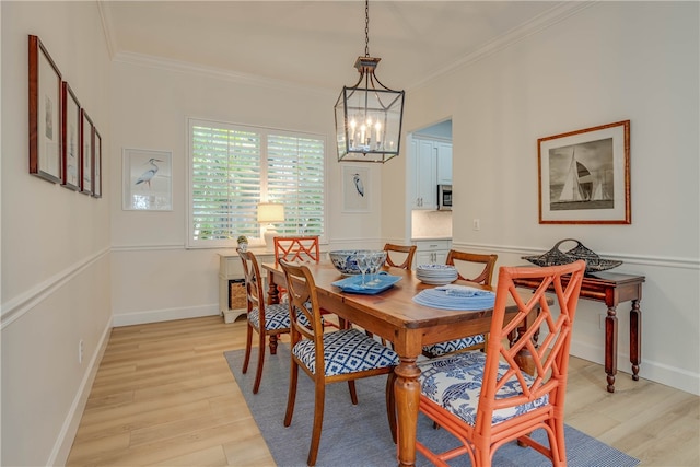 dining area featuring ornamental molding, light wood-type flooring, a chandelier, and baseboards