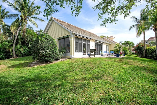 rear view of property featuring a yard, a patio area, and a sunroom