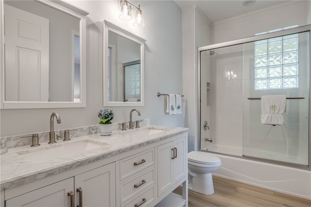 full bath featuring double vanity, toilet, a sink, and wood finished floors