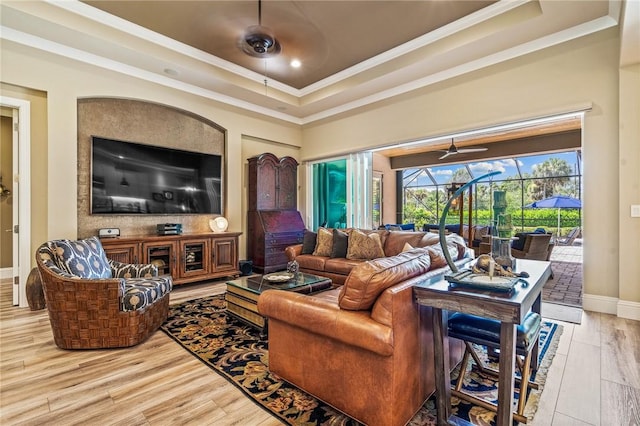 living room with light hardwood / wood-style floors, a raised ceiling, and crown molding