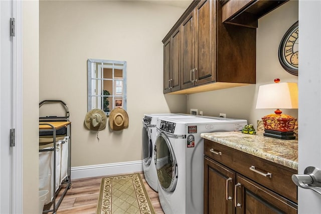 clothes washing area with cabinets, separate washer and dryer, and light hardwood / wood-style flooring