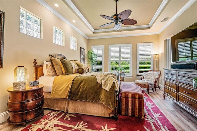 bedroom with hardwood / wood-style flooring, ceiling fan, a raised ceiling, and crown molding