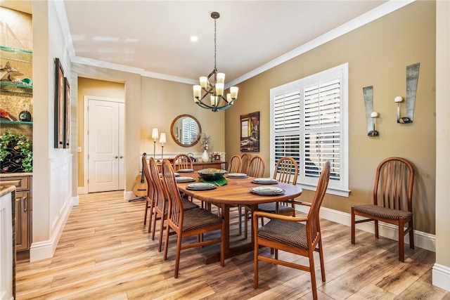 dining area featuring light wood-type flooring, crown molding, and a chandelier