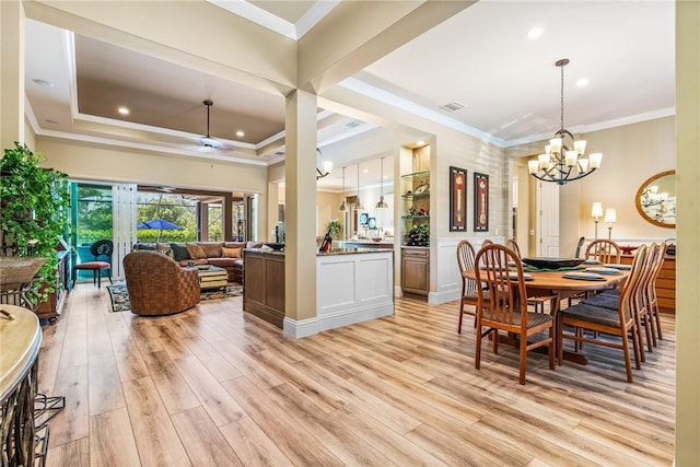 dining area with ceiling fan with notable chandelier, a raised ceiling, light wood-type flooring, and ornamental molding