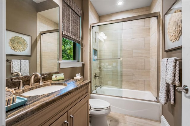 full bathroom featuring tile patterned flooring, vanity, toilet, and bath / shower combo with glass door