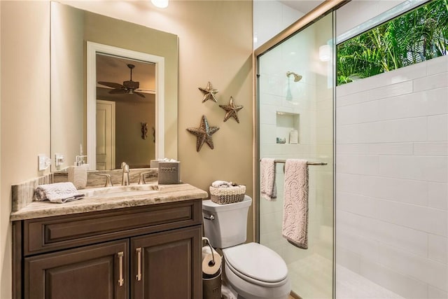 bathroom with ceiling fan, vanity, an enclosed shower, and toilet