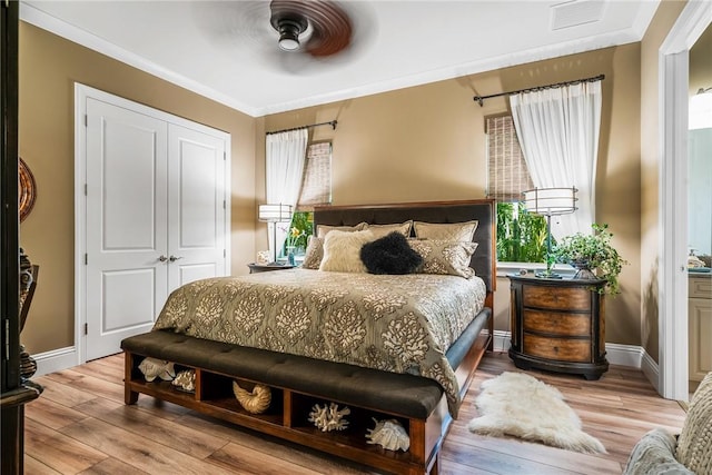 bedroom with ceiling fan, light wood-type flooring, multiple windows, and a closet