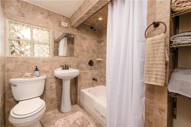 bathroom with shower / bathtub combination with curtain, toilet, and tile walls