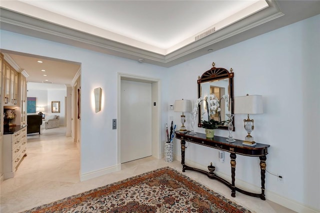 hallway with a raised ceiling, ornamental molding, and elevator