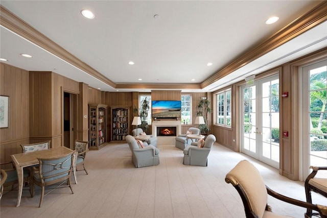 interior space featuring a tray ceiling, wood walls, french doors, and crown molding