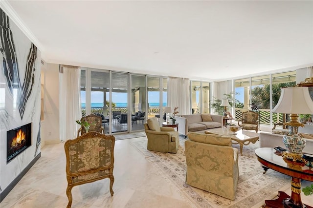 living room with a premium fireplace, a water view, ornamental molding, and a wall of windows