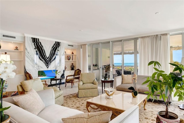 living room with built in shelves, crown molding, and a water view