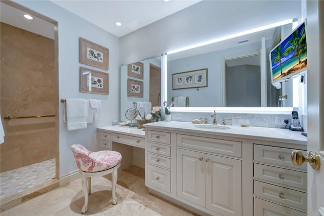 bathroom featuring a tile shower and vanity