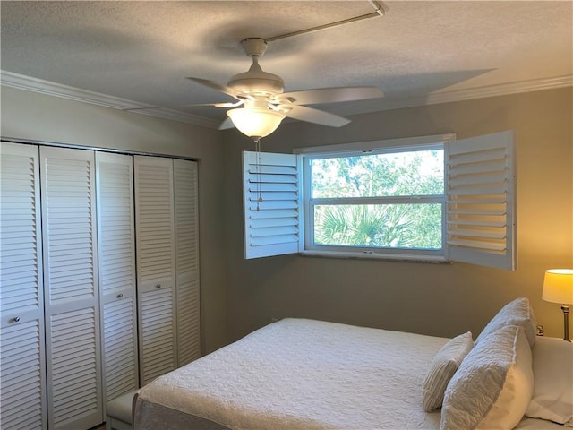 bedroom with a textured ceiling, ceiling fan, crown molding, and a closet