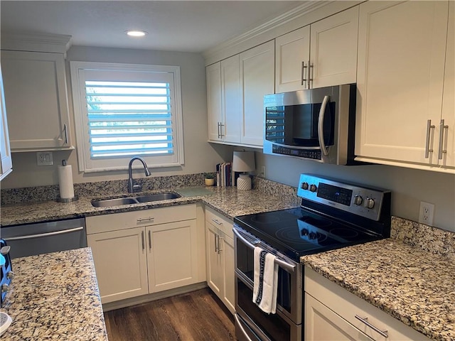 kitchen with light stone countertops, sink, dark hardwood / wood-style floors, white cabinets, and appliances with stainless steel finishes