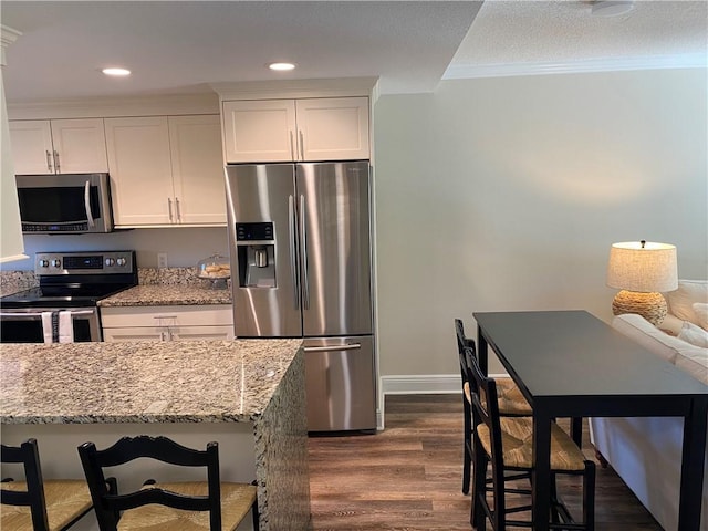 kitchen with a breakfast bar area, light stone countertops, white cabinets, and stainless steel appliances