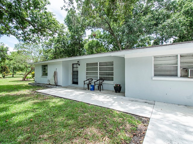 rear view of house with a patio and a lawn