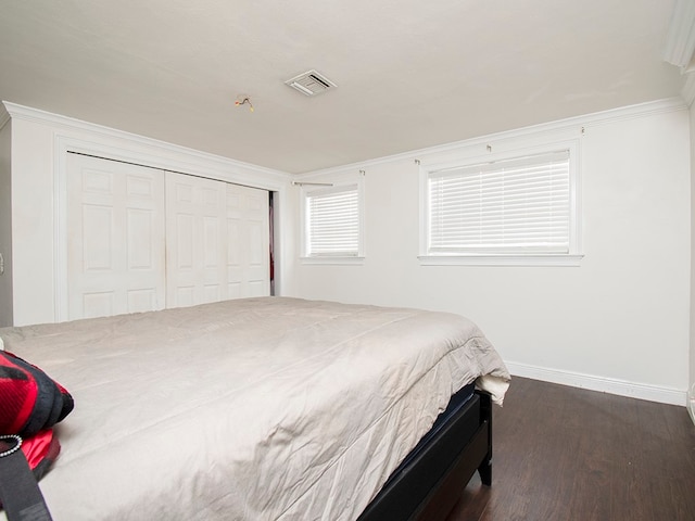 bedroom featuring dark wood-type flooring, a closet, and crown molding