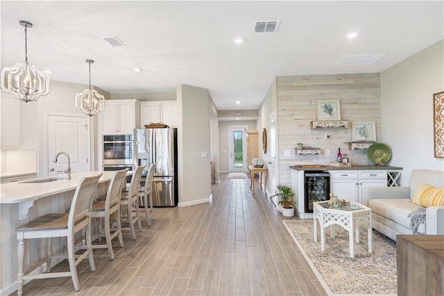 kitchen featuring wine cooler, appliances with stainless steel finishes, sink, white cabinets, and light hardwood / wood-style flooring