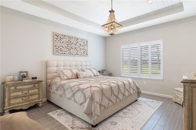 bedroom with an inviting chandelier, a tray ceiling, hardwood / wood-style floors, and wooden ceiling