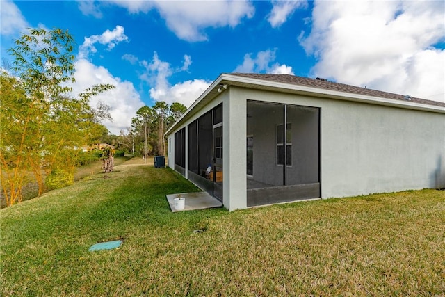 rear view of property with a sunroom, central AC, and a lawn