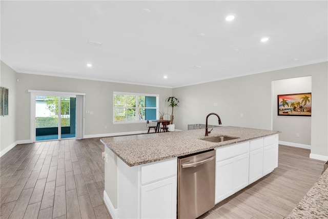 kitchen featuring sink, light stone counters, a center island with sink, stainless steel dishwasher, and white cabinets