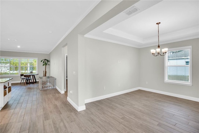 unfurnished room featuring an inviting chandelier, a tray ceiling, ornamental molding, and light wood-type flooring