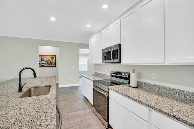 kitchen with light stone counters, white cabinetry, appliances with stainless steel finishes, and sink