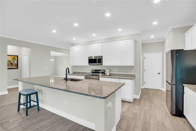 kitchen with appliances with stainless steel finishes, sink, a center island with sink, and white cabinets