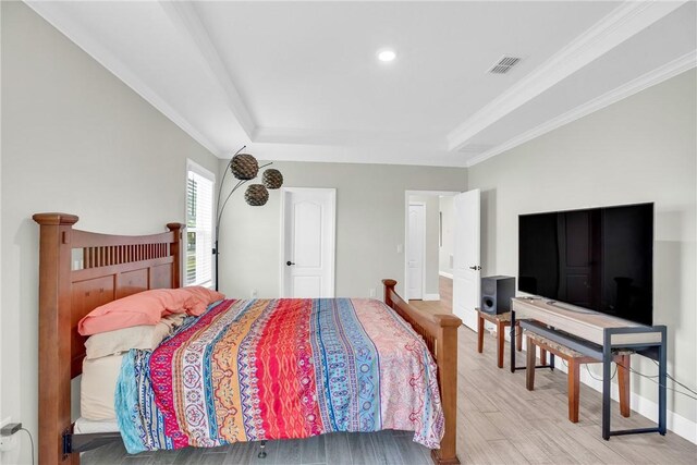 bedroom with a tray ceiling, ornamental molding, and light hardwood / wood-style floors