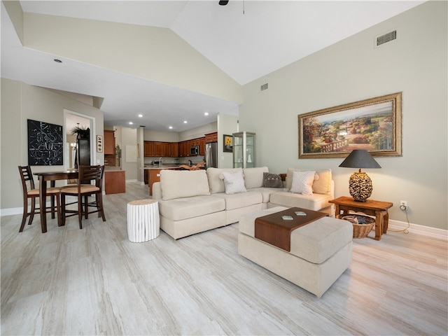 living room featuring light wood-type flooring and high vaulted ceiling