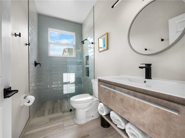 bathroom featuring tiled shower, vanity, and toilet