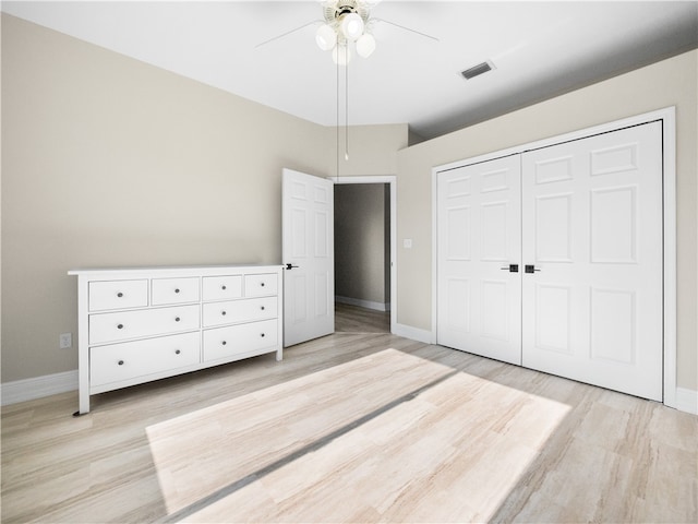 unfurnished bedroom with light wood-type flooring, ceiling fan, and a closet