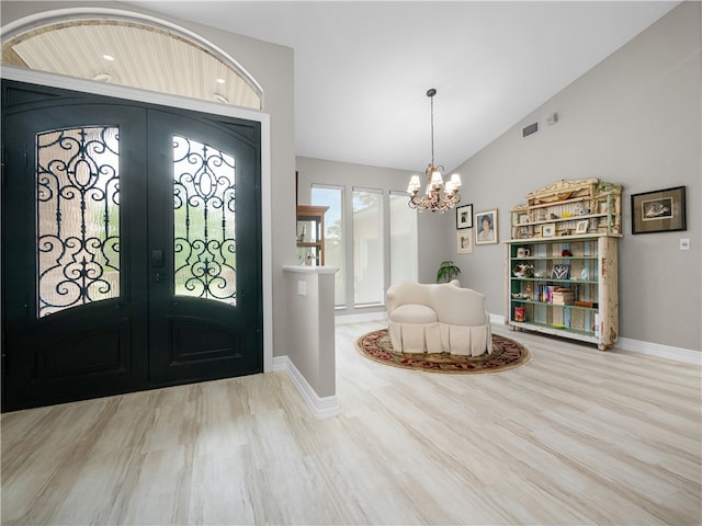 entrance foyer with an inviting chandelier, lofted ceiling, french doors, and wood-type flooring