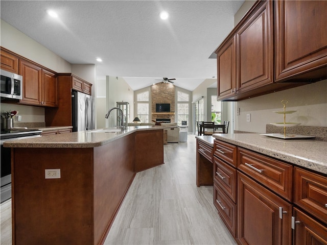 kitchen featuring stainless steel appliances, lofted ceiling, sink, a textured ceiling, and a kitchen island with sink