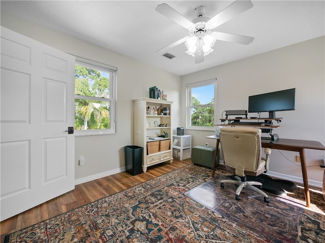 office space featuring ceiling fan, a wealth of natural light, and dark hardwood / wood-style floors