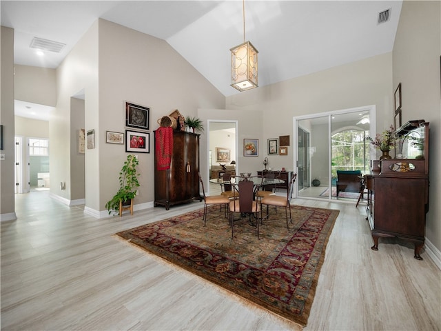 dining area with light hardwood / wood-style flooring and high vaulted ceiling