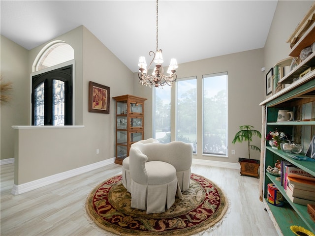 living area with light wood-type flooring, lofted ceiling, and a notable chandelier