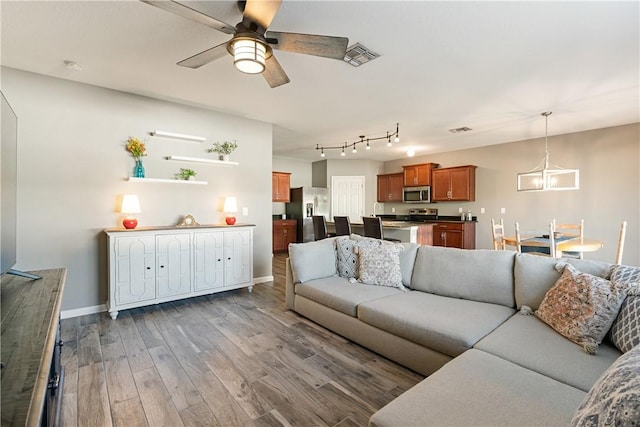 living room with hardwood / wood-style floors and ceiling fan with notable chandelier