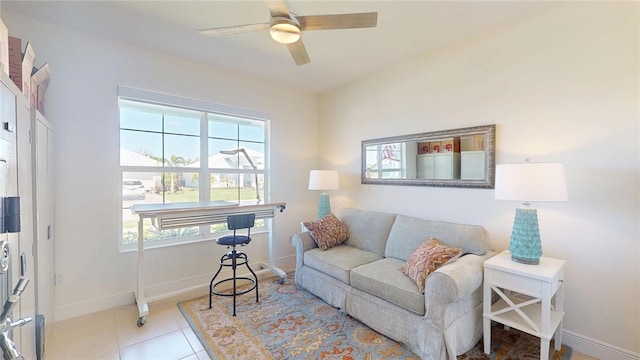 tiled living area featuring a wealth of natural light, a ceiling fan, and baseboards