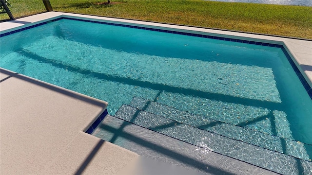 outdoor pool featuring a lawn