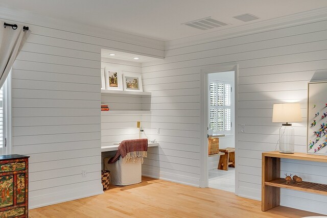 mudroom with light hardwood / wood-style floors, wooden walls, and crown molding