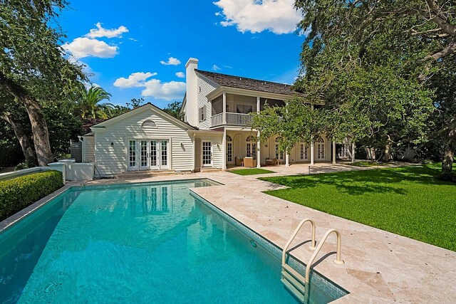 back of house featuring a lawn, a balcony, a patio, and french doors