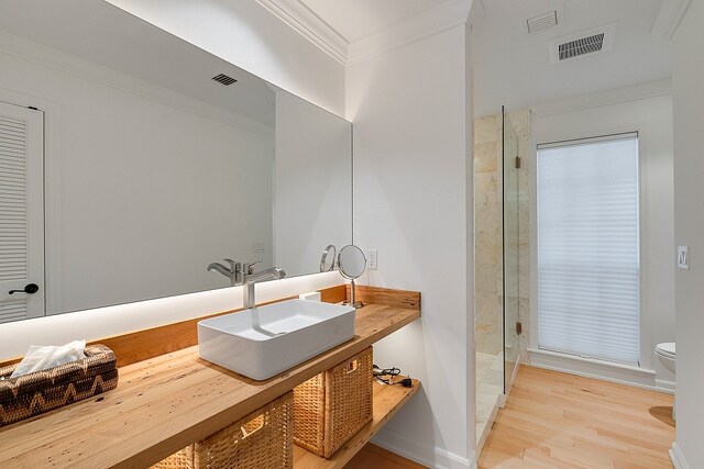 bathroom with hardwood / wood-style flooring, vanity, toilet, and crown molding