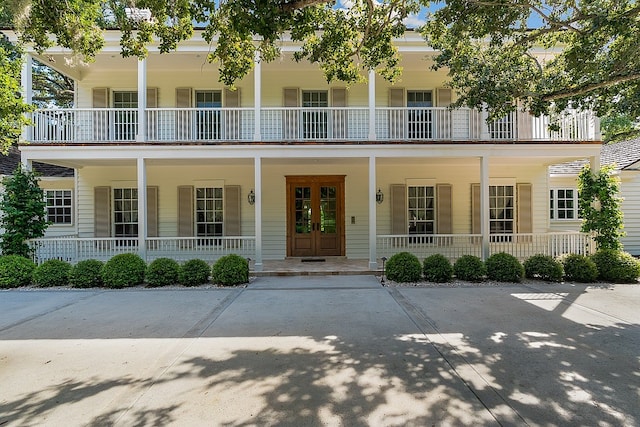 entrance to property with a balcony, covered porch, and french doors