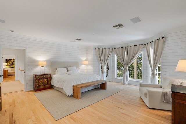 bedroom featuring light wood-type flooring, wooden walls, and access to exterior