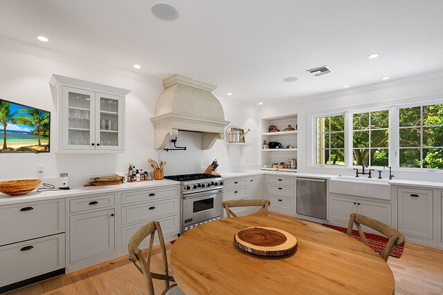 kitchen featuring light hardwood / wood-style flooring, sink, crown molding, appliances with stainless steel finishes, and premium range hood