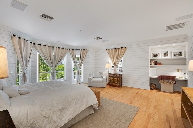 bedroom featuring access to exterior, wooden walls, and hardwood / wood-style flooring