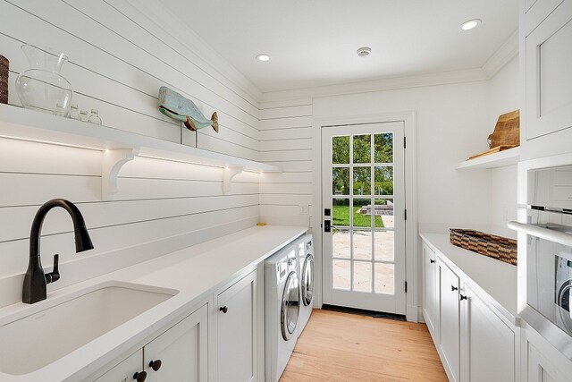 laundry area with separate washer and dryer, crown molding, light wood-type flooring, cabinets, and sink