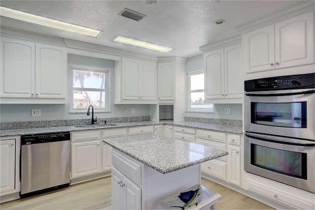 kitchen with light stone countertops, sink, white cabinets, and stainless steel appliances